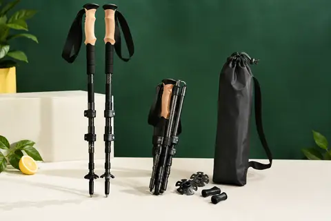 Bâtons de randonnée pliables noirs en carbone avec poignées en liège et accessoires posés à côté