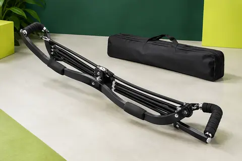 Appareil de musculation portable noir à ressorts, posé dans un studio sportif sobre