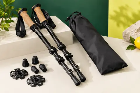 Paire de bâtons de randonnée noirs en fibre de carbone avec poignées en liège et accessoires, présentée en studio.