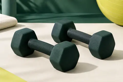 Paire d’haltères en néoprène à têtes anti-roulis présentée sur un fond de studio sportif sobre