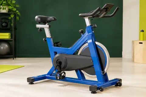 Vélo d’appartement bleu à cadre en H, selle large, pédales avec cale-pieds et volant d’inertie caréné