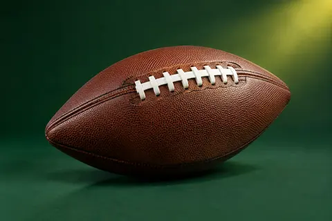 Ballon de football américain Wilson brun à double couture présenté seul sur un fond vert de studio