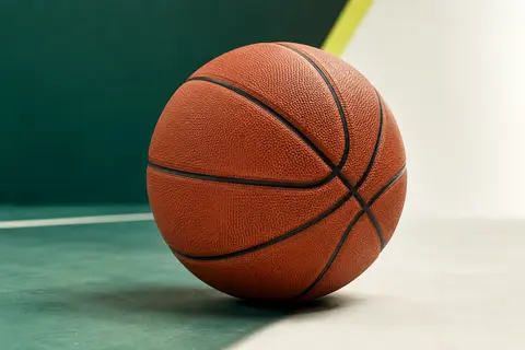 Ballon de basket marron en caoutchouc avec canaux profonds, posé sur un fond sportif vert et blanc