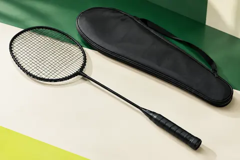Raquette de badminton noire à tête isométrique avec cordage installé et housse posée à côté